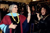Outgoing WHC Chancellor Kristin Clark high fives Lemoore College grads.